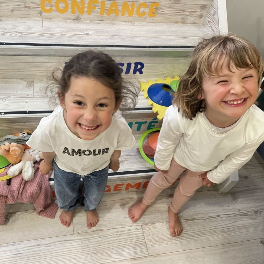 des enfants jouent à un jeux en anglais deux petites filles sourient avec une pile d'objets derriere elles